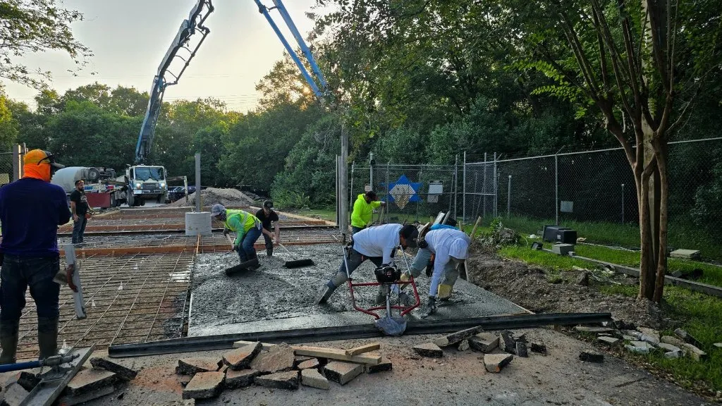 Crew placing and finishing concrete slab with pump truck