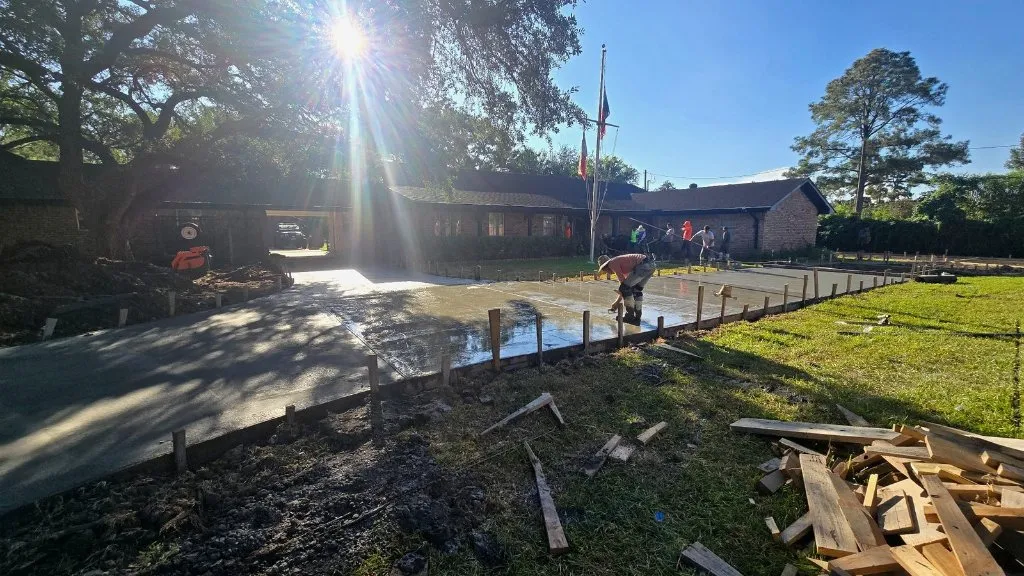 Concrete flatwork pour with crew and pump hose on site